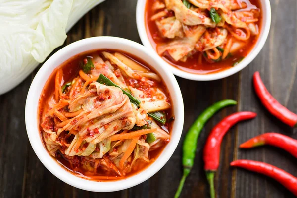 Kimchi cabbage in a bowl and chili on wooden background, Korean food, Top view