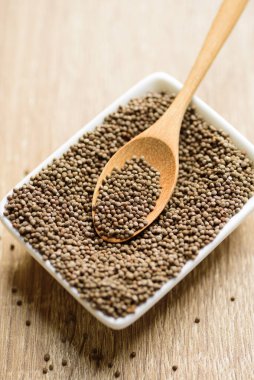 Tahta zemin üzerinde kaşık olan bir kasede organik perilla tohumu, Asya yemeklerinde sağlıklı bitkisel tohum.