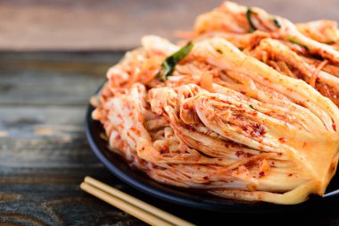 Tabakta kimchi lahanası, ahşap masada çubuklar, Kore yemeği.