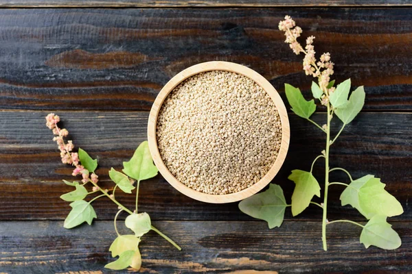 Organic raw brown quinoa seed in a bowl and quinoa plant on wooden background, Healthy food, Top view