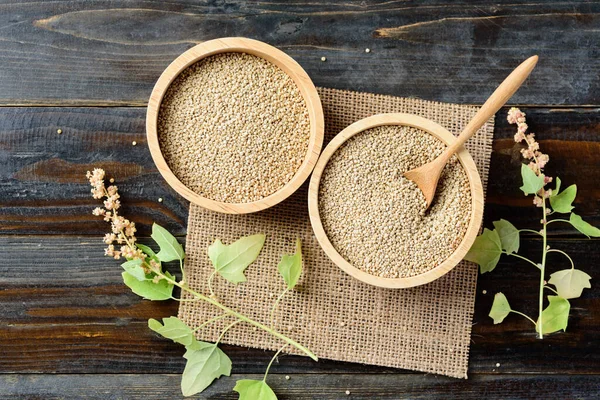 Organic raw brown quinoa seed in a bowl with spoon and quinoa plant on wooden background, Healthy food, Top view