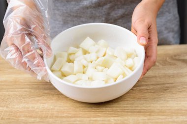 Kimchi turpu pişirme, birinci adım; taze dilimlenmiş turpu bir kasede tuzla karıştırmak.