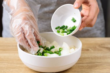 Kimchi turp pişirme, ikinci adım; dilimlenmiş taze soğanla turpu bir kasede karıştırmak.