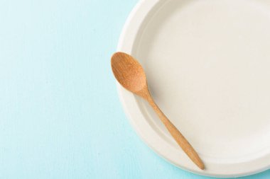 Biyolojik çözünebilir tabak, gübrelenebilir tabak ya da pastel arka planda ahşap kaşıklı tek kullanımlık eko tabak.