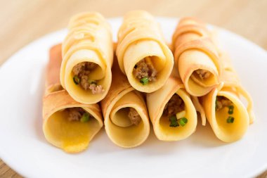 Tayland tatlısı (Khanom Tokyo), beyaz tabakta kıymalı krep rulosu.