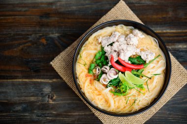 Baharatlı pirinç eriştesi çorbası (Thai Tom Yum) ahşap arka planda, Asya yemekleri, Top View