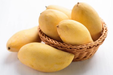 Beyaz masada bir sepette olgun mango meyvesi, tropikal meyve, Tayland mangosu (Nam Dok Mai)
