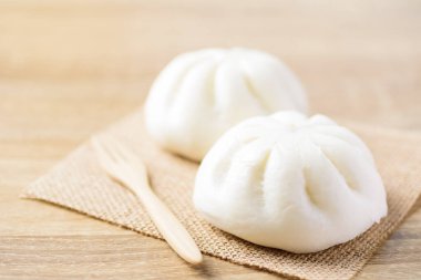 İnce dilimlenmiş domuz etiyle doldurulmuş buğulanmış çörekler ve ahşap masaya tuz, Asya yemekleri.