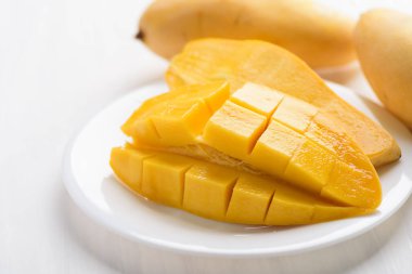 Beyaz tabakta küp şeklinde dilimlenmiş olgun mango meyvesi, tropik meyve, Tayland mangosu (Nam Dok Mai) 