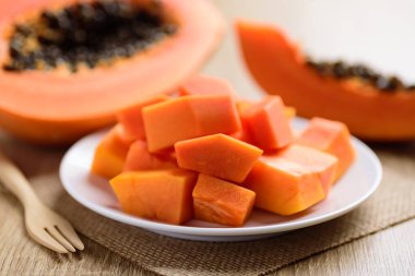 Dilimlenmiş papaya meyvesi tabakta ve çatalla yemeye hazır, tropikal meyve.