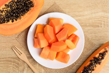Dilimlenmiş papaya meyvesi tabakta ve çatalla yemeye hazır, tropikal meyve.