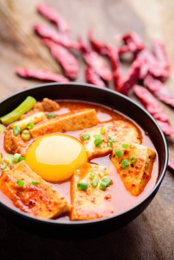 Tahta arka planda bir kasede tofu ve yumurta ile Kimchi çorbası, Kore yemeği (Kimchi Jjigae)