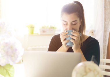 Evinden dizüstü bilgisayarla çalışan güzel, mutlu bir kadın. Genç bayan.