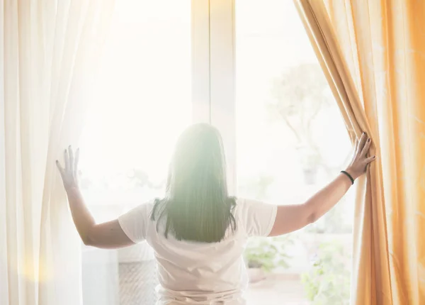 Mädchen öffnet Vorhänge in einem Schlafzimmer. Frau öffnet den Vorhang für — Stockfoto