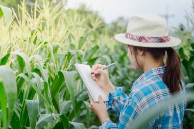 Çiftçi kadın notlar alır üstünde tarımda bir defter bir kalem ile Bahçe.