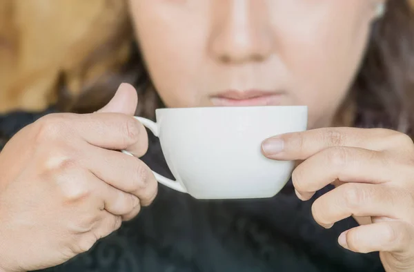 A woman holding a cup of coffee to drink. — Stock Photo, Image