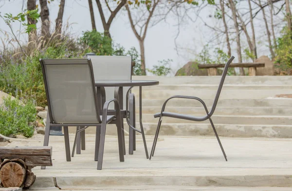 Table et chaises debout sur le sol de ciment dans le jardin — Photo