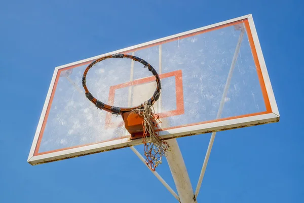 old basketball hoop without net in blue sky background