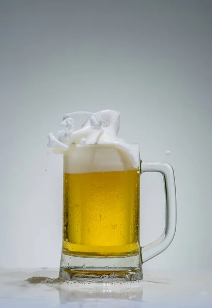 Glas bier met schuim spatten op een grijze achtergrond — Stockfoto