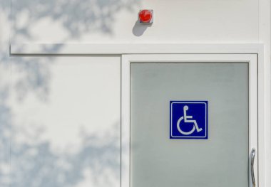 Uluslararası Engelliler gölgeler yaprak beyaz duvar üzerinde cam kapı ve kırmızı siren ışığı için işaretleme.