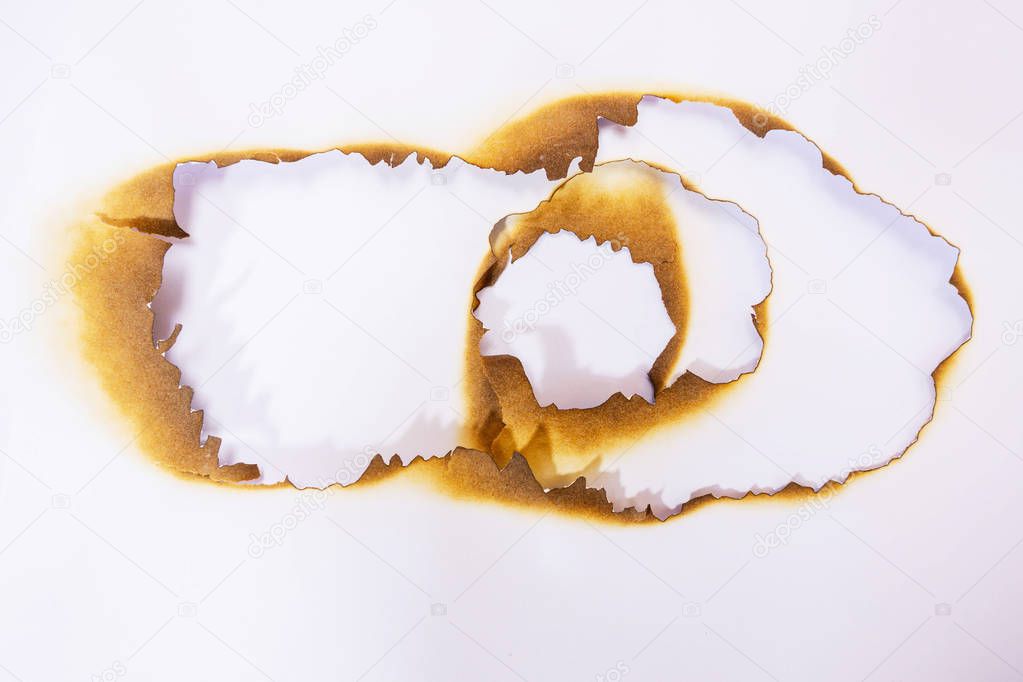 close up hole paper with edges burned on white background