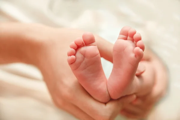 Die kleinen niedlichen Fußsohlen der neugeborenen Füße sind in den Händen des Vaters. — Stockfoto