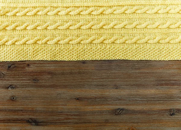 Knited yellow fabric with braid pattern on the wooden background — ストック写真