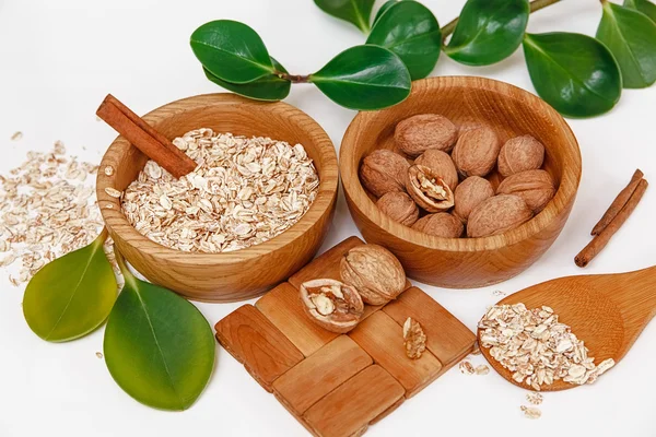 Hay con nueces y avena laminada en las placas de madera con palos de canela, soporte de madera, cuchara, hojas verdes, alimentos orgánicos frescos saludables en el fondo blanco —  Fotos de Stock