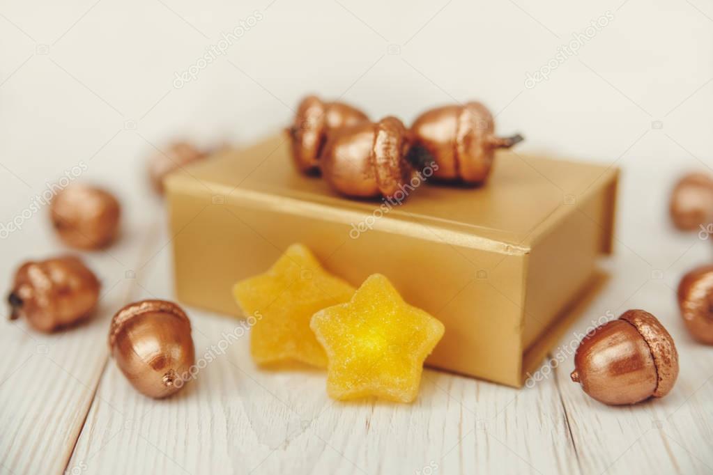 Christmas composition.Golden present box and golden acorns.White wooden table,jujube stars.