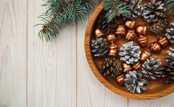 クリスマスの組成物。木製のプレートで黄金のドングリ、白いコーン ツリー バンチ — ストック写真