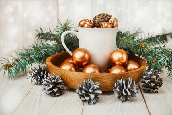 De samenstelling van de kerst met witte cup, fir banch, kegels en gouden ballen. Nieuwe Year.Wooden-tabel. — Stockfoto