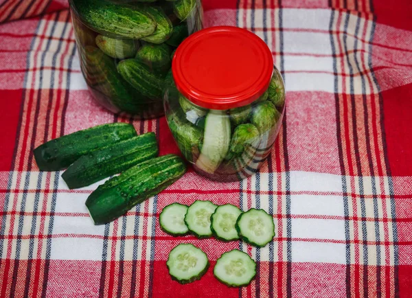 Preserved cucumbers and pieces in jars with red covers.