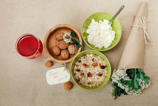 Υγιή οργανικά Breakfast.Walnuts,Oatmeal andc ottage Cheese.Green κεραμικά και ξύλινα Plates.Glass με κόκκινο Drink.Wish κίτρινη κάρτα με μπουκέτο — Φωτογραφία Αρχείου