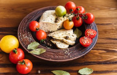 homemade cheese,tomatoes with herb spice in rural pottery.wooden background. clipart