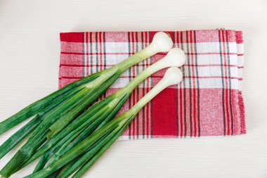 Onay kırmızı masa örtüsü üzerinde yeşil taze soğan. Sebze, vitaminler. Üstten Görünüm.