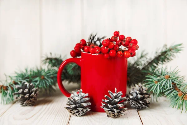 De samenstelling van Kerstmis met rode cup, fir banch, kegels en planten van viburnum. Nieuwjaar. — Stockfoto