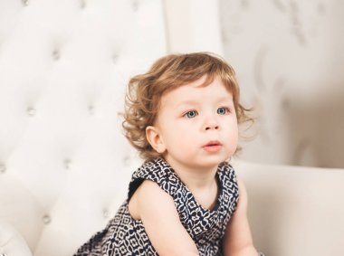 Sandalyede oturan mavi gözlü küçük sevimli güzel kız