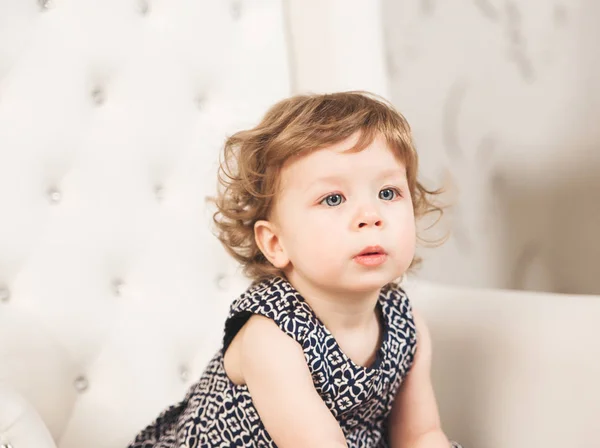 Μικρό χαριτωμένο όμορφη κοπέλα με μπλε μάτια που κάθεται στην καρέκλα — Φωτογραφία Αρχείου