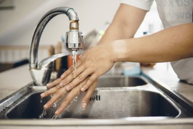 Koronavirüsün yayılmasını önlemek için her zaman temiz ellerle başlayın (Covid-19). Asyalı bir adamın evde ellerini yıkarken çekilmiş görüntüsü.