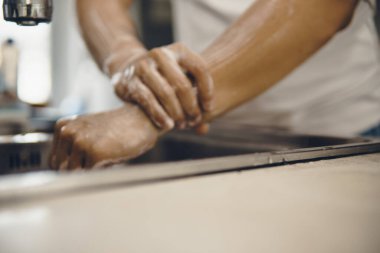 Koronavirüsün yayılmasını önlemek için her zaman temiz ellerle başlayın (Covid-19). Asyalı bir adamın evde ellerini yıkarken çekilmiş görüntüsü.