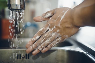 Koronavirüsün yayılmasını önlemek için her zaman temiz ellerle başlayın (Covid-19). Asyalı bir adamın evde ellerini yıkarken çekilmiş görüntüsü.