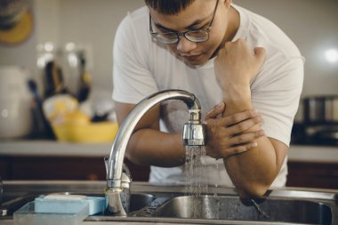 Koronavirüsün yayılmasını önlemek için her zaman temiz ellerle başlayın (Covid-19). Asyalı bir adamın evde ellerini yıkarken çekilmiş görüntüsü.