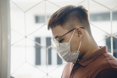 İş yerinde koronavirüse karşı koruma. Genç Asyalı adam hijyenik yüz maskesi takıyor. 2019-NCoV ya da Covid 19 salgını tarafından şok edildi. Stüdyo çekimi