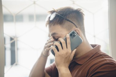 Yeni Coronavirus Covid-19 zatürree salgını sırasında beyaz cerrahi maske takan ve cep telefonu kullanan genç bir Asyalı 'ya yaklaş.
