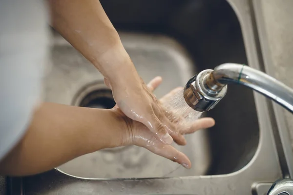 Koronavirüsün yayılmasını önlemek için her zaman temiz ellerle başlayın (Covid-19). Asyalı bir adamın evde ellerini yıkarken çekilmiş görüntüsü.