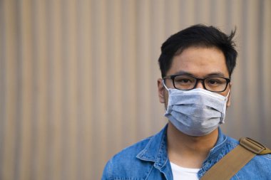 Mikropları, zehirli dumanı ve tozu önlemek için süpermarketin dışında koruyucu maske takan genç bir adamın portresi. Bakteriyel enfeksiyonun önlenmesi Corona virüsü veya Covid 19 sokaklarda ve bahçelerde.