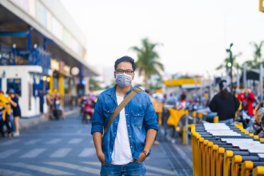 Mikropları, zehirli dumanı ve tozu önlemek için süpermarketin dışında koruyucu maske takan genç bir adamın portresi. Bakteriyel enfeksiyonun önlenmesi Corona virüsü veya Covid 19 sokaklarda ve bahçelerde.