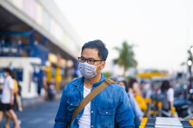 Mikropları, zehirli dumanı ve tozu önlemek için süpermarketin dışında koruyucu maske takan genç bir adamın portresi. Bakteriyel enfeksiyonun önlenmesi Corona virüsü veya Covid 19 sokaklarda ve bahçelerde.