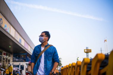 Mikropları, zehirli dumanı ve tozu önlemek için süpermarketin dışında koruyucu maske takan genç bir adamın portresi. Bakteriyel enfeksiyonun önlenmesi Corona virüsü veya Covid 19 sokaklarda ve bahçelerde.