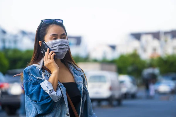 Sokakta Cep Telefonu Kullanırken Ameliyat Maskesi Takan Genç Bir Kadın — Stok fotoğraf